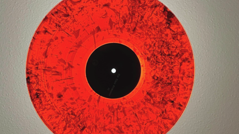 Two hands hold a red, semi-transluscent vinyl record