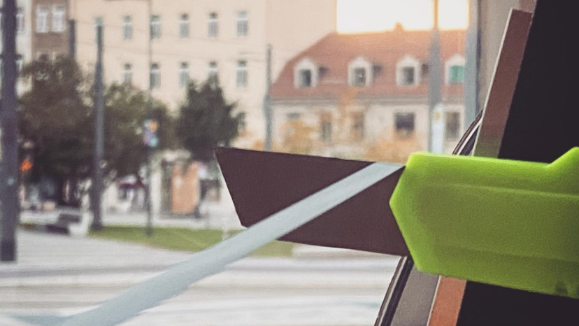 Ein Cutter hinter vor einem Fenster, im Hintergrund eine unscharfe Berliner Straßenzeile