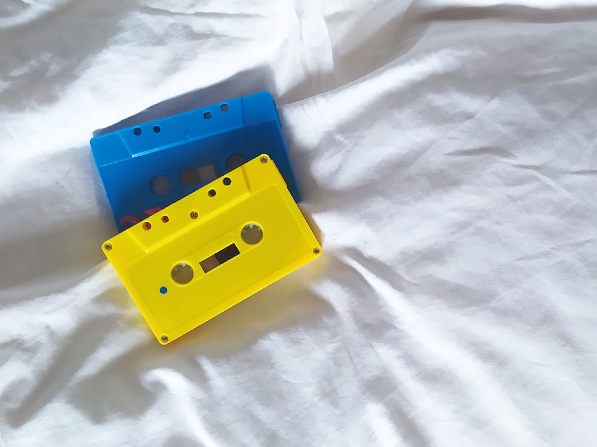 Zwei Musik-Kassetten liegen auf einem Bett.