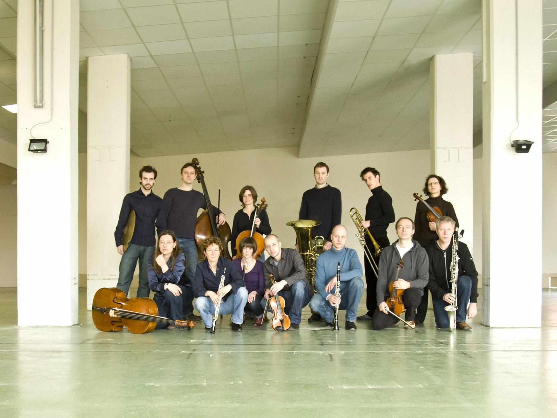 Die Mitglieder des Ensemble KNM in einer Betonhalle, mit ihren Instrumenten.