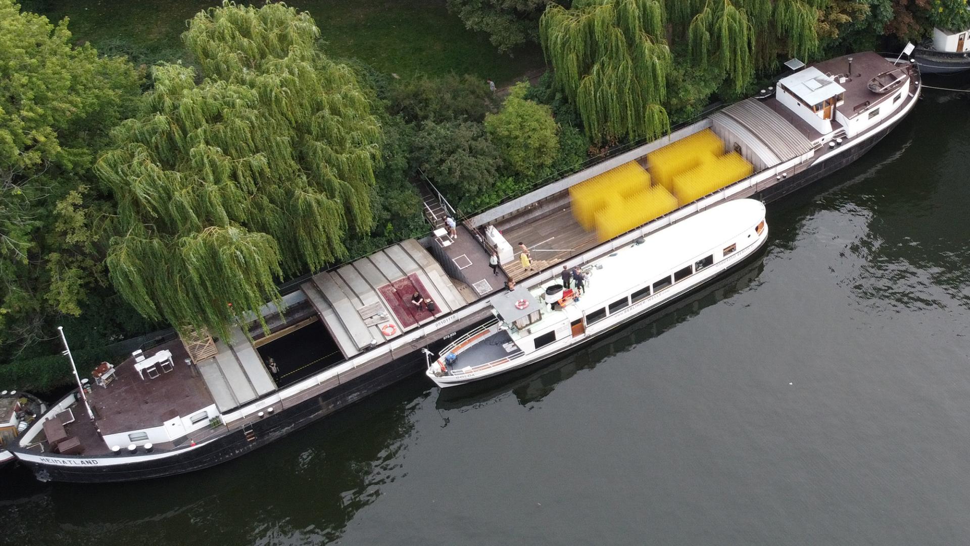 Zwei Boote liegen am Ufer eines Flusses an. Man sieht sie von oben.