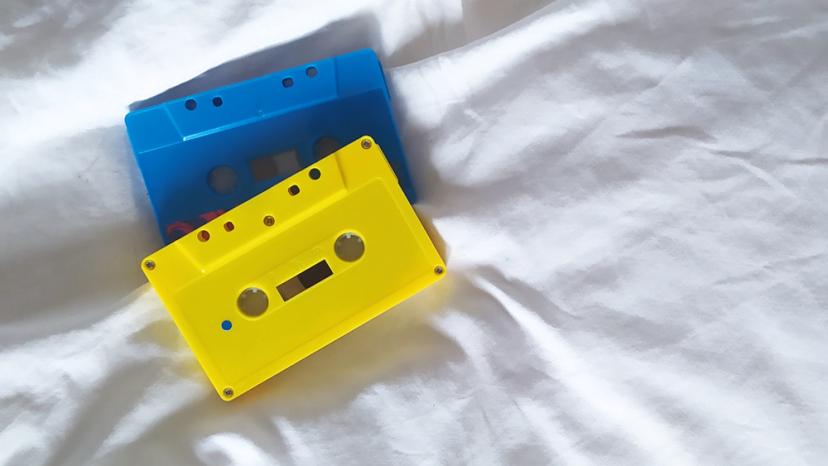 Zwei Musik-Kassetten liegen auf einem Bett.